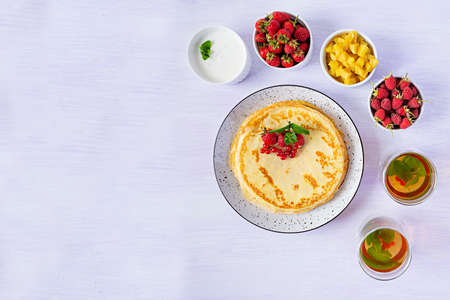 Pancakes with caramelized apples, raspberries, strawberries and red currants. Brunch with green tea...