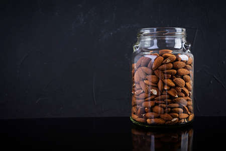 Almonds nuts in a jar. Set of nuts isolated on dark backgroundの写真素材