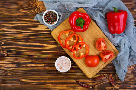 Pepper, tomato, salt, different spice on wooden background