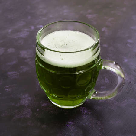 Mug of green beer on dark background