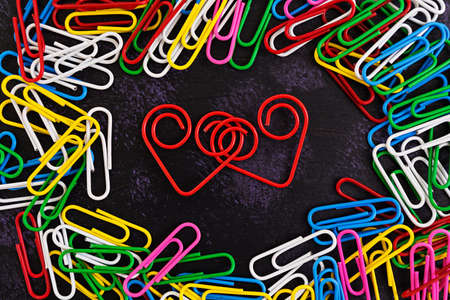 Colored paper clips isolated on dark backgroundの写真素材