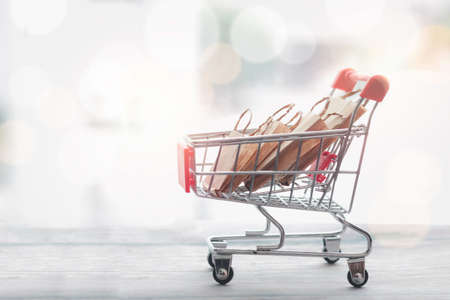Mini trolley with shopping bags on wooden table, shopping, and commerce business, buying and sell...
