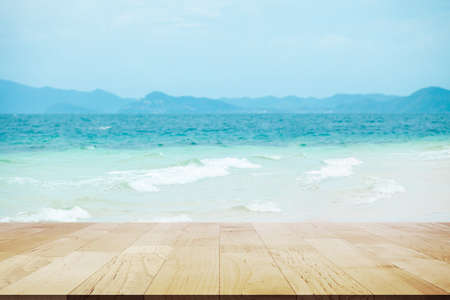 Empty wooden table top with lights bokeh on beautiful white sand beach and turquoise water. Holiday summer beach backgroundの写真素材