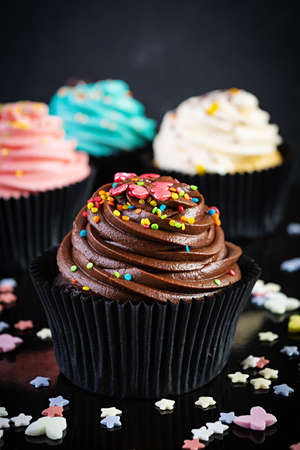 Tasty colorful cupcakes isolated on dark background. Delicious cupcake