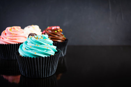 Tasty colorful cupcakes isolated on dark background. Delicious cupcakeの写真素材
