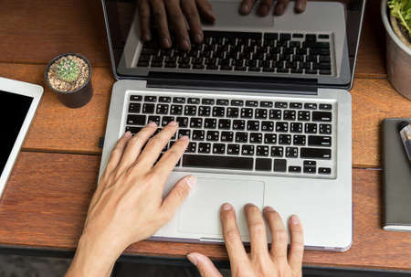 Young business man hand using laptop on wooden table. top viewの写真素材