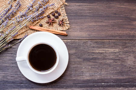Cup of coffee and lavender flower on dark wooden table background with copy space