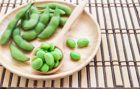 Fresh green soybeans in wooden spoon on wooden background.の写真素材