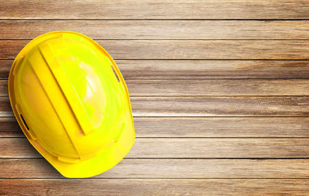 Top view yellow safety helmet on wood table background in office workplace. Copy space for any...