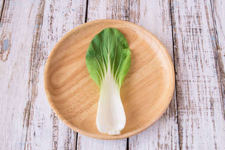 fresh leaves of romaine lettuce in a rustic wooden plate on white wooden tableの写真素材