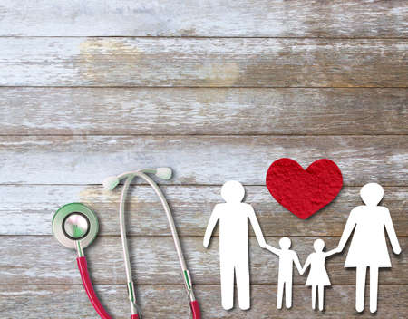 Top view with paper cut of family on wood table with red hearts and red stethoscope. Copy space for your design.の写真素材