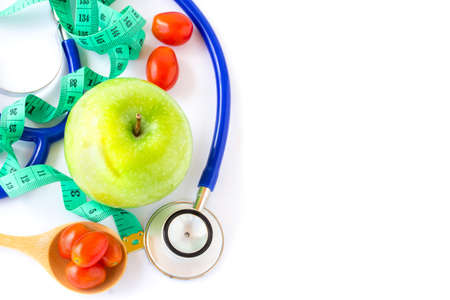 Green apple,red tomatos, measuring tape and stethoscope on a white backgroundの写真素材
