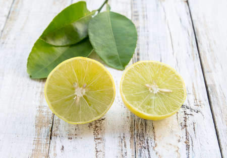 Freshly cut half and whole lemons on white wooden table background