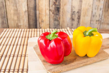 Sweet red and yellow pepper in wooden cutting boards on wood tableの写真素材