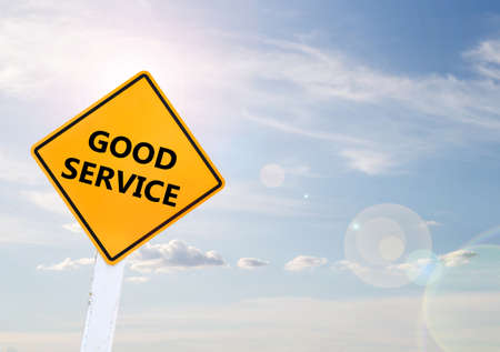Text for GOOD SERVICE on yellow road sign with blur blue sky backgroundの写真素材