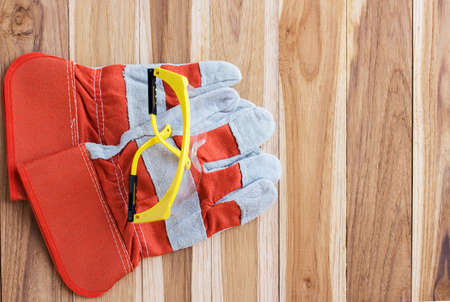 Protective gloves and goggles. Standard construction safety equipment on wooden table with copy spaceの写真素材