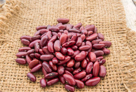 Red beans in burlap sack on wooden table backgroundの写真素材