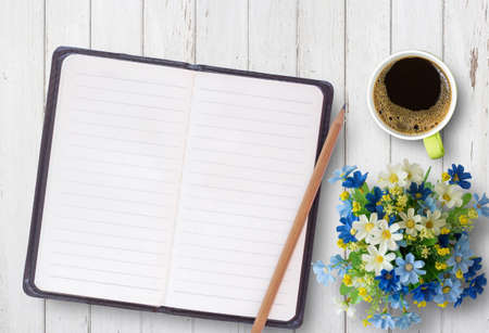 Top view of office desk table with open spiral notebook, pencil,cup of coffee and flower on white wood table background. Business and education concept.の写真素材