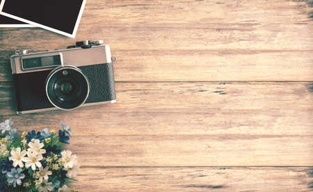 Top view image of vintage camera with two blank photo frames on wood table or office desk background. space for design. retro filteredの写真素材
