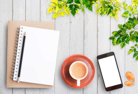 Top view open notebook,smart phone,pencil and cup of coffee on rustic white wooden table background. Cozy autumn breakfast. Fall bucket list. Flat lay style.の写真素材
