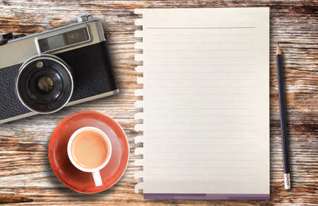 Top view cup of coffee,retro camera,pencil and blank paper on wooden table background. Coffee on office desk. Food and drink concept.の写真素材