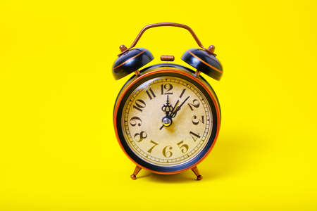 Alarm clock on a yellow background, bright and sunny