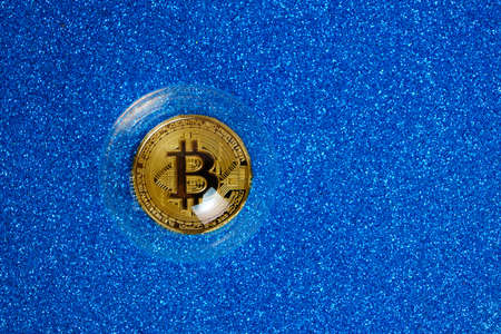 Bitcoin cryptocurrency coin in a soap bubble on a blue backgroundの写真素材