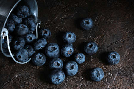 Blueberry berries spilled from metal bucket onto wooden tableの写真素材