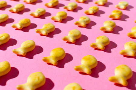 Cookies in form of fish on a pink background in bright light with hard shadows.Close up.の写真素材