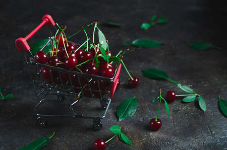 Bright red cherry in a shopping cart on an old concrete floor.