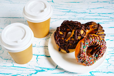 Chocolate doughnuts and takeaway coffee on a light backgroundの写真素材