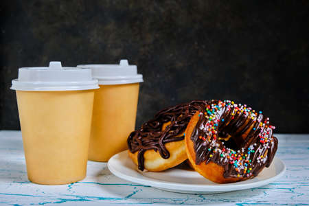 Chocolate doughnuts and takeaway coffee on a dark backgroundの写真素材