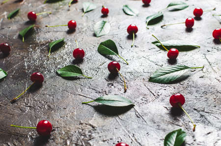 Cherry berries with leaves on the old, rustic concrete floor with a Sunny dawn.の写真素材
