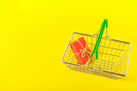 Gift in the shopping cart on a yellow backgroundの写真素材