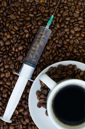 Syringe, cup of coffee and coffee beans the view from the topの写真素材