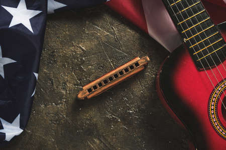 Star spangled flag, guitar and harmonica on a dark background. Musical instrument and flag of the United States of Americaの写真素材