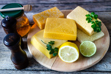 Variety of cheese on the old rustic table.Cheese, spices, lemon and lime in natural light.の写真素材