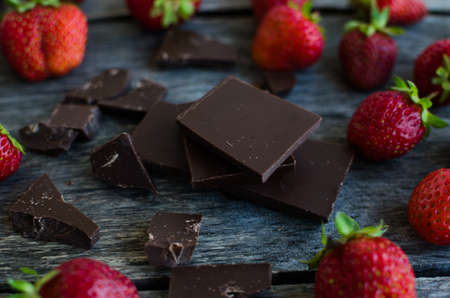Strawberries and pieces of broken chocolate on the old wooden backgroundの写真素材