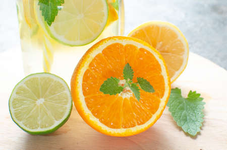Jar of lemonade made of lemon, lime, orange and mint with a closed lid and a tube in it against background concrete floor.の写真素材