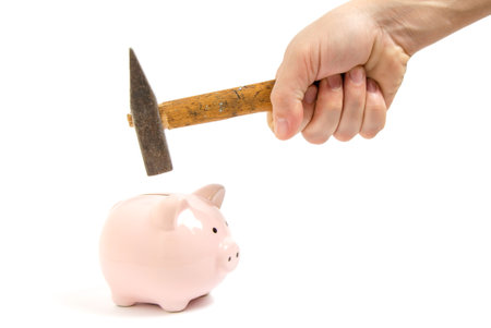 Man hand smashes a pink piggy Bank on a white background with a hammer.の写真素材