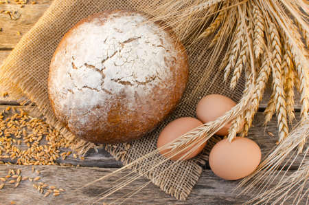 Loaf of black bread on old wooden table, the rays of the morning sunの写真素材