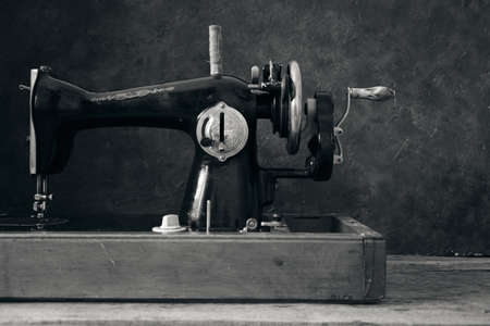 Old, retro, vintage sewing machine on a dark background of an abstract wallの写真素材