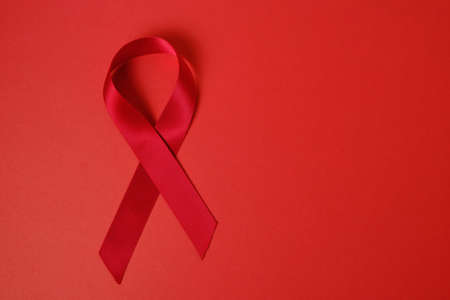 Red ribbon on red background is symbol of AIDS and drug addictionの写真素材