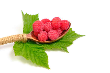 Raspberry berry in a wooden spoon with a green leaf on a white background
