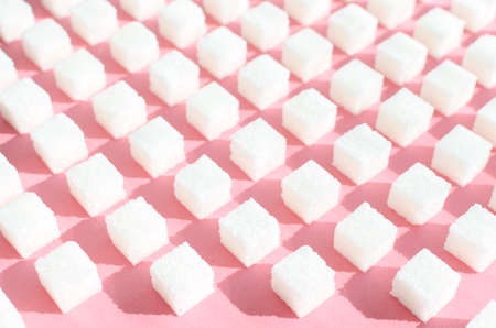Refined sugar on pink background.Cubes of sweet and white sugar in geometricshape. Hard shadows and blinds.の写真素材