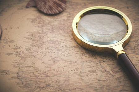 Old retro map of world is pressed with shells and magnifying glass.Vacation, recreation, and travelの写真素材