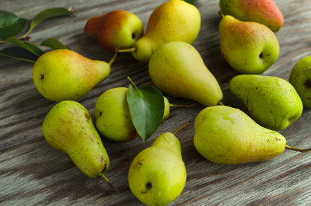 Scattered ripe pear and leaves on old wooden table