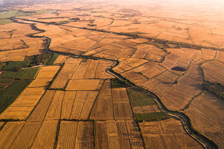 Aerial view of agricultural barren fields with irrigation canal in farmland at countrysideの写真素材