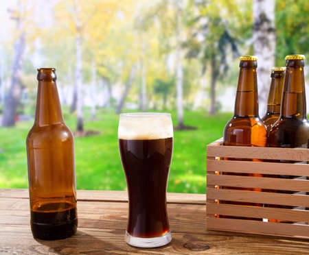 Beer in glass,bottles on wooden table with blurred city park on background, food and drink concept,copy space,selective focusの写真素材