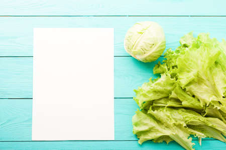 Cabbage and lettuce with recipe paper and copy space on blue wooden table.の写真素材